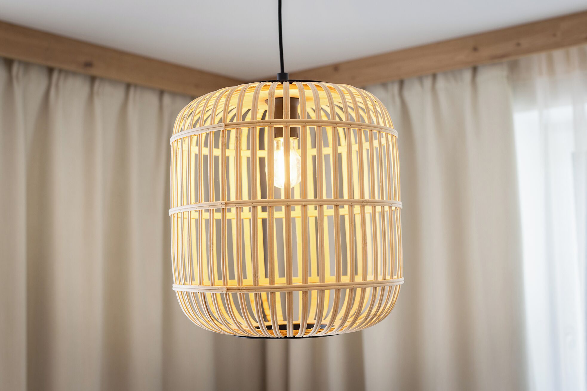 A hanging light fixture with a cylindrical, woven design.