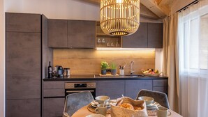 Une cuisine moderne avec des meubles de couleur sombre, un plan de travail en bois et un coin repas agrémenté d’assiettes, de bols et de tasses.