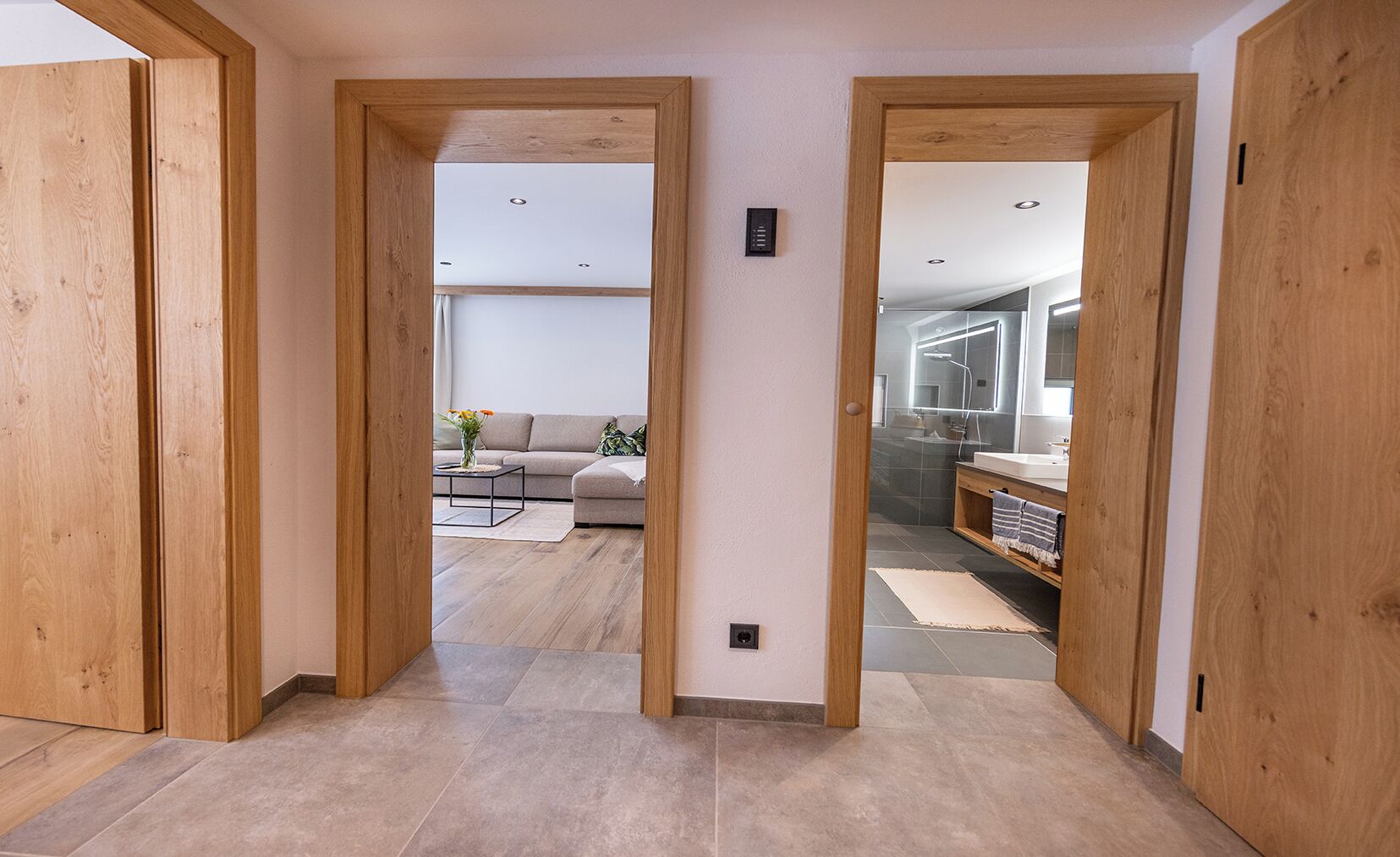 A hallway with wooden doors leading to a living room and bathroom.