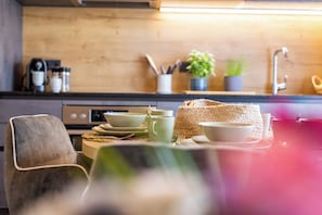 A kitchen with a wooden countertop, a coffee maker, and a woven basket. - Lennis Apartments by we rent (Zell am See)