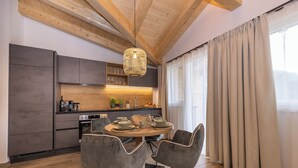 Une cuisine moderne avec des poutres en bois, une table à manger avec des chaises et une grande fenêtre avec des rideaux.