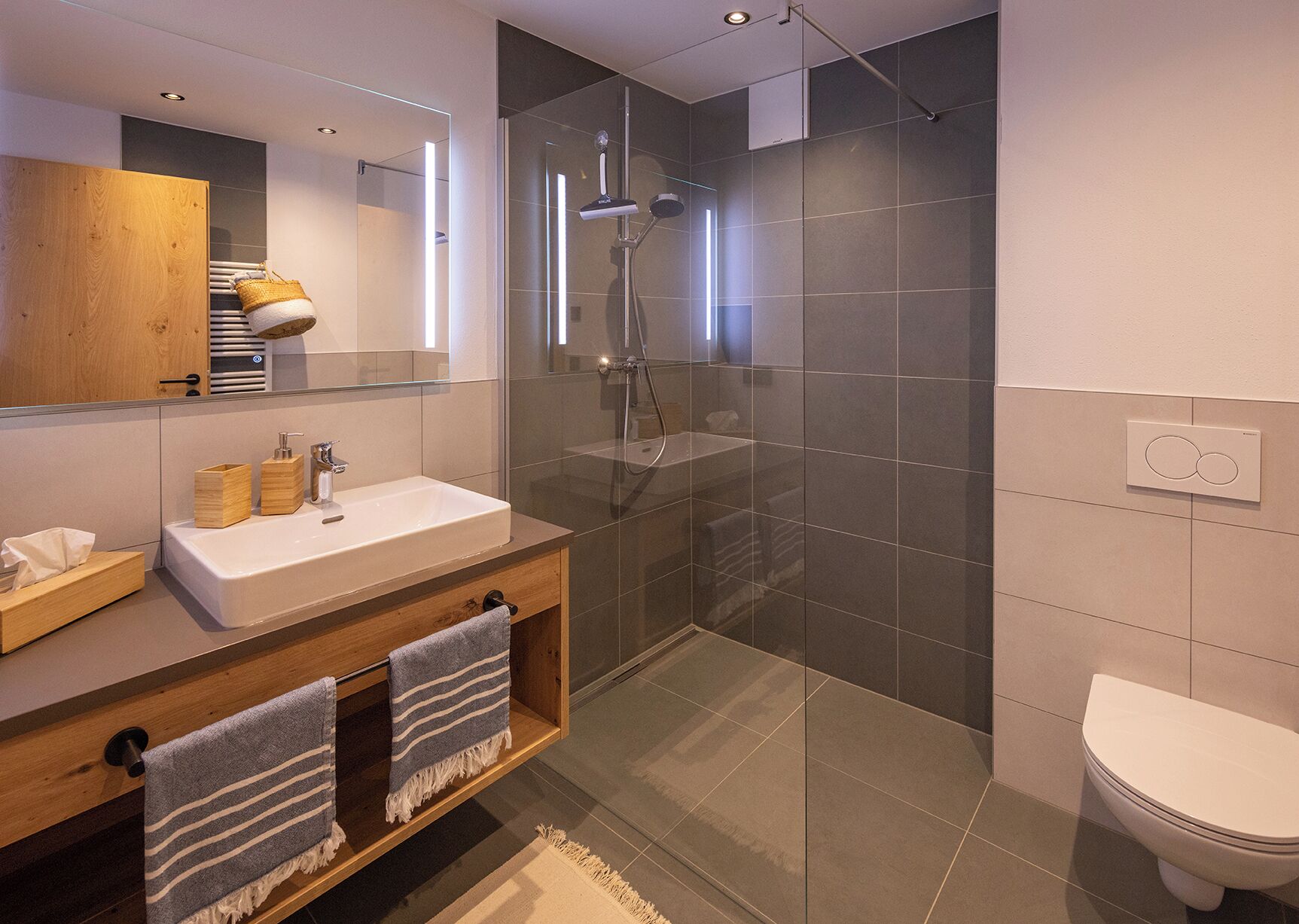 A modern bathroom with a glass-enclosed shower, a wooden vanity, a white sink, and a toilet.