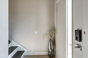 A staircase leading to a landing, a door with a lock, and a vase with flowers on the wall. - Work & Play! Gem w/ Fire Pit, 3 Mi to Dtwn Dallas (Dallas)