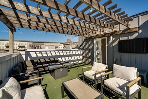Um terraço no telhado com área de estar externa, pérgola e vista para a cidade.