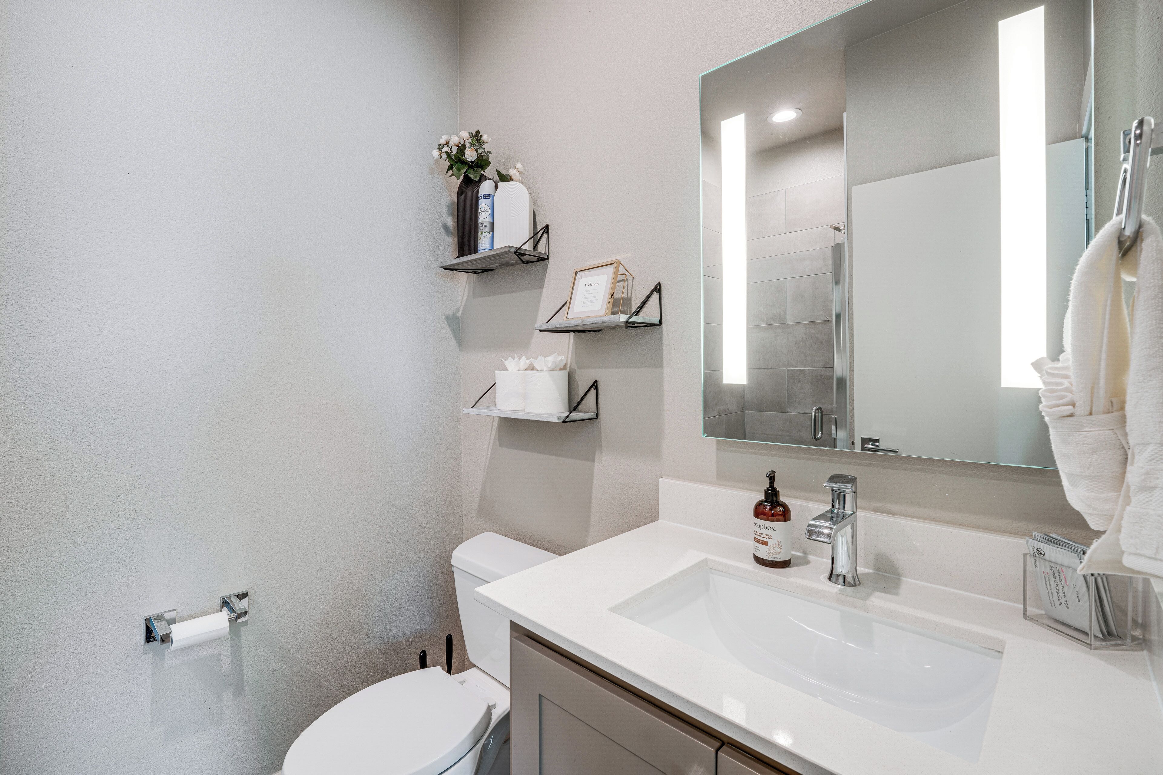 A bathroom with a white sink, a mirror, a toilet, and a towel rack.