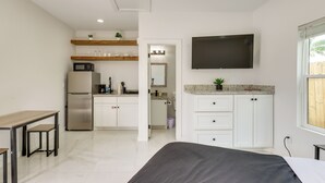 Una cocina moderna con armarios blancos, un microondas y un refrigerador. Hay una zona de comedor con una mesa y sillas.