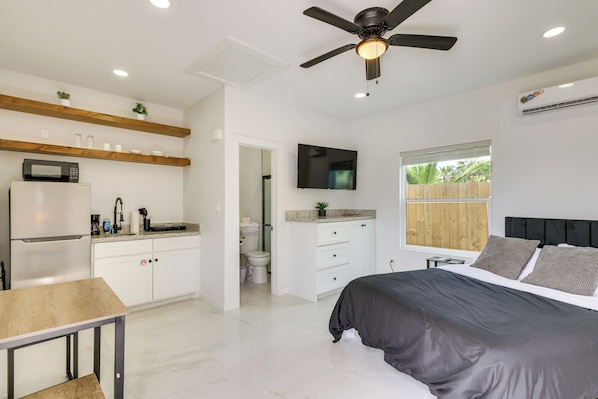 Un dormitorio moderno con cama, televisor y ventilador de techo.