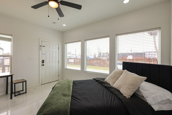 A bedroom with a bed, a ceiling fan, and large windows. - Community Pool! Walkable South Padre Island Studio (South Padre Island)