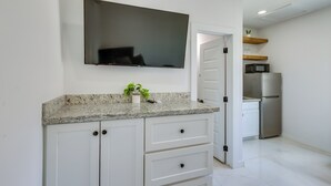 A kitchen with a flat-screen TV, white cabinets, granite countertop, and stainless steel appliances. - Easy South Padre Beach Retreat w/ Pool Access (South Padre Island)