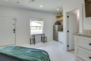 Un dormitorio con cama, escritorio y kitchenette.