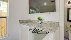 A bathroom with a granite countertop, a mounted TV, a potted plant, and a white door. - Groups Welcome! SPI Studio on Multi-unit Property (South Padre Island)