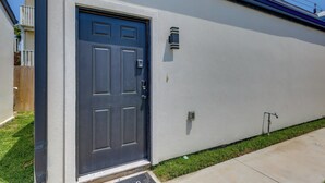 A residential building with a dark-colored front door, a mailbox, and a small outdoor light fixture. - Groups Welcome! SPI Studio on Multi-unit Property (South Padre Island)