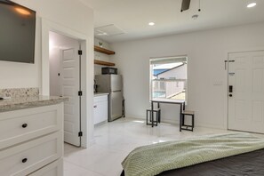 Ein Schlafzimmer mit Bett, Schreibtisch, Stuhl, Fenster und Tür.