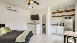 Ein Schlafzimmer mit einem Bett, einem Deckenventilator, einer Klimaanlage und einem an der Wand montierten Fernseher.