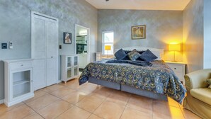 Quarto com cama, mesas de cabeceira, guarda-roupa, espelho e ventilador de teto.