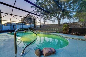 A pool with a metal ladder, surrounded by a covered area with trees and a fence. - Resort-style Pool & Yard: Luxe Duplex Near Disney! (Davenport)
