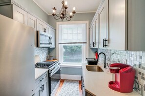 A compact kitchen with a stove, oven, microwave, and a red coffee maker. - Walkable Schenectady Getaway: 2-unit Campus Hub (Schenectady)