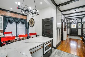 A kitchen with a marble island, red chairs, a clock, and a bicycle light fixture. - Walkable Schenectady Getaway: 2-unit Campus Hub (Schenectady)