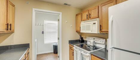 A kitchen with wooden cabinets, a white refrigerator, a microwave, an oven, and a sink.