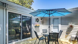 A covered patio with a table and chairs, a sliding glass door, and a blue umbrella. - 2 Mi to Myrtle Beach Boardwalk: 2 King Beds! (Myrtle Beach)