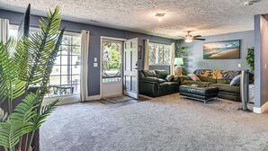 A living room with a couch, ottoman, ceiling fan, and a painting on the wall. - 2 Mi to Myrtle Beach Boardwalk: 2 King Beds! (Myrtle Beach)