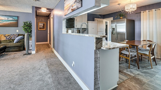 A modern kitchen with a central island, a dining area with a table and chairs, and a living room with a sofa and a plant. - 2 Mi to Myrtle Beach Boardwalk: 2 King Beds! (Myrtle Beach)