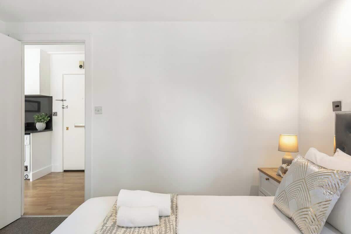 A bedroom with a bed, bedside tables, a lamp, and a door leading to a bathroom.