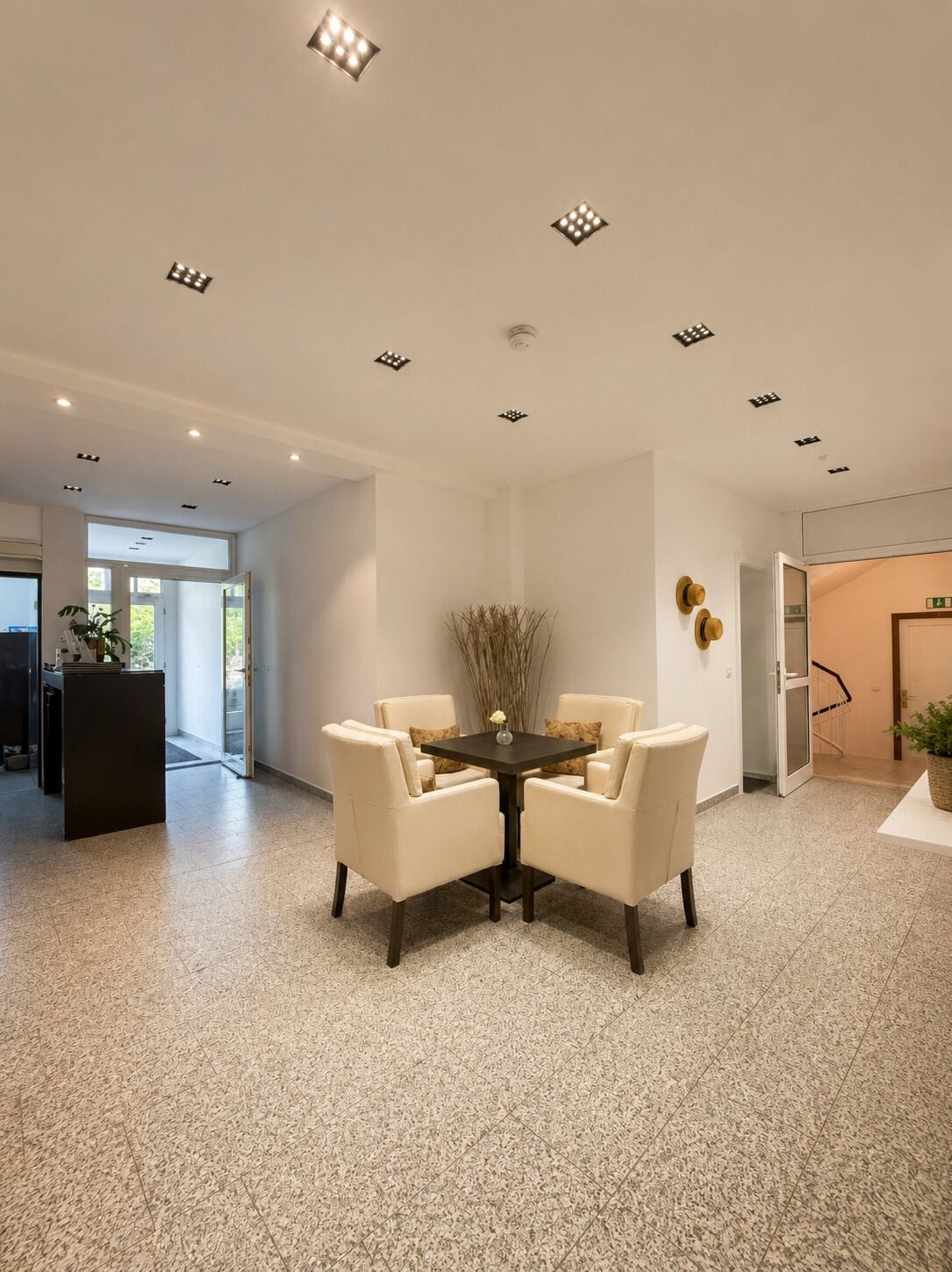 A modern interior with a round table, four chairs, and recessed ceiling lights.