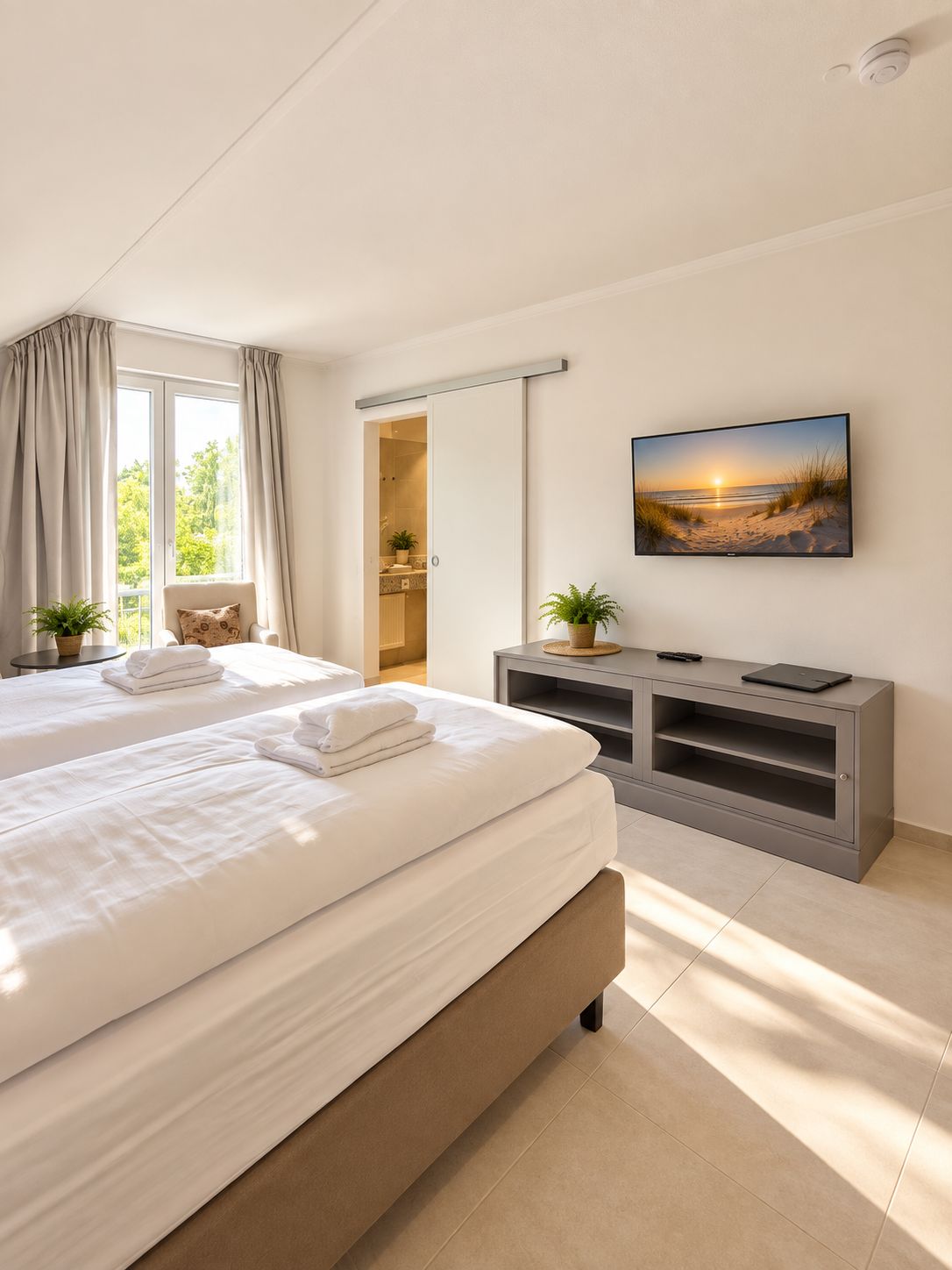 Una habitación de hotel con una cama grande, televisión y vistas a la playa.