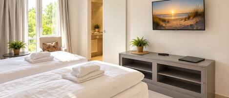 Una habitación de hotel con una cama grande, televisión y vistas a la playa.