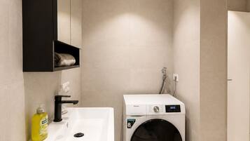 A modern bathroom with a sink, mirror, and built-in washing machine.