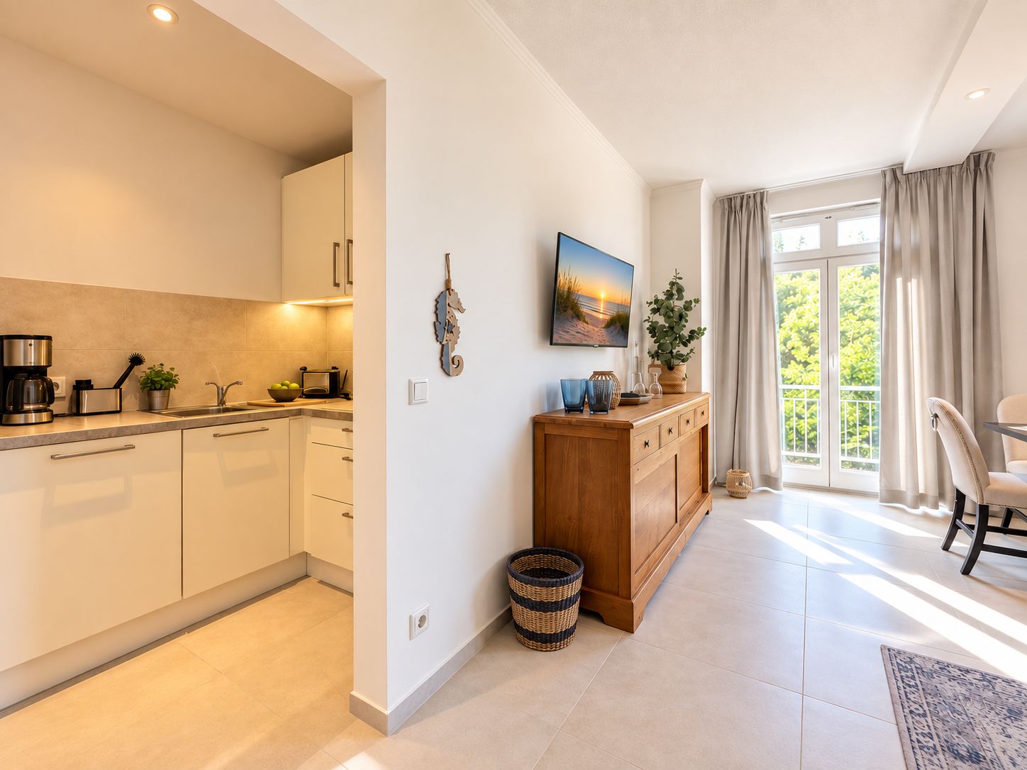 Eine moderne Küche mit weißen Schränken, einem Holzsideboard und einem großen Fenster mit Vorhängen.