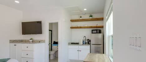 A bedroom with a bed, a bedside table, a ceiling fan, and a TV mounted on the wall.