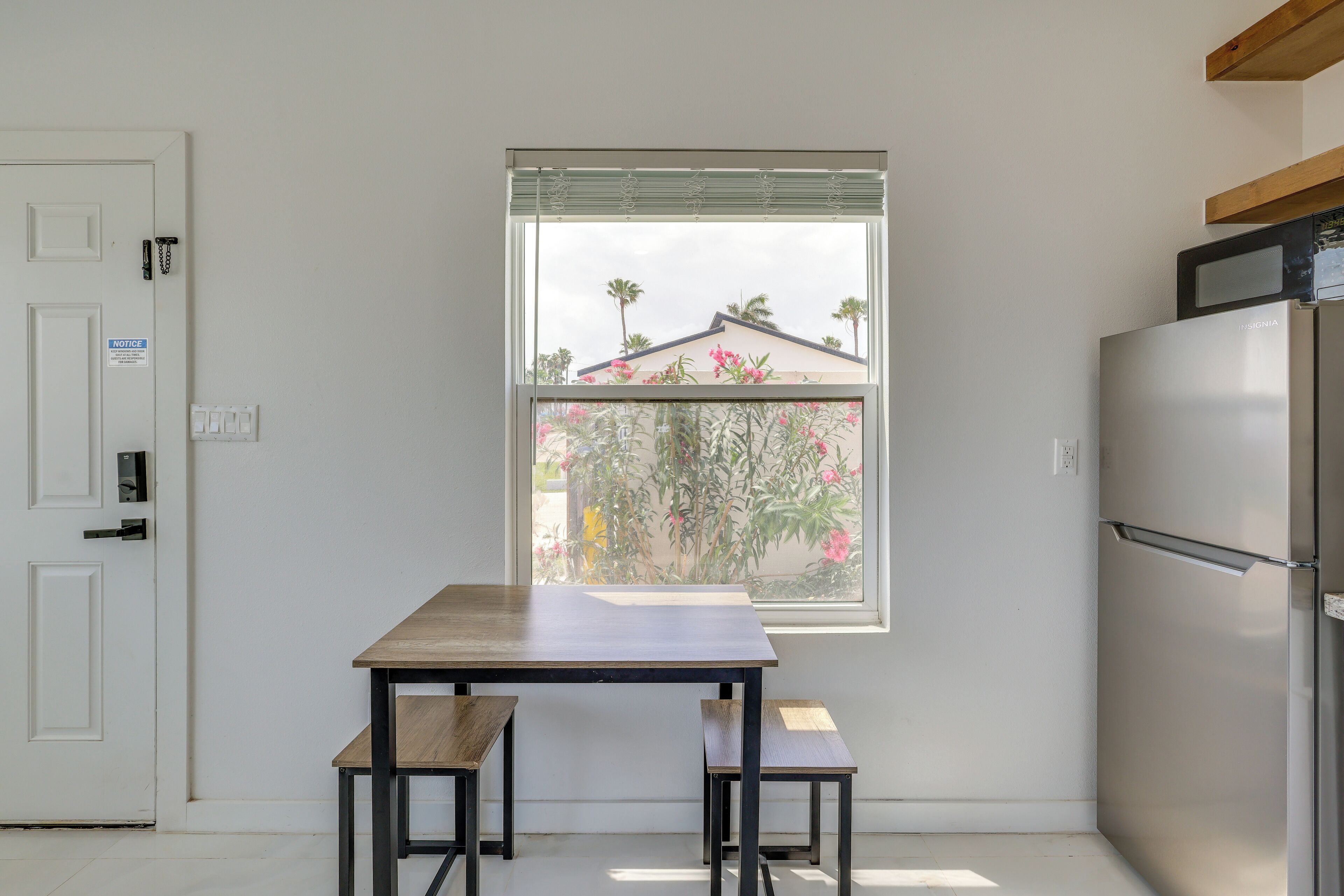 Eine Küche mit Fenster, einem Kühlschrank und einem Tisch mit Bänken.