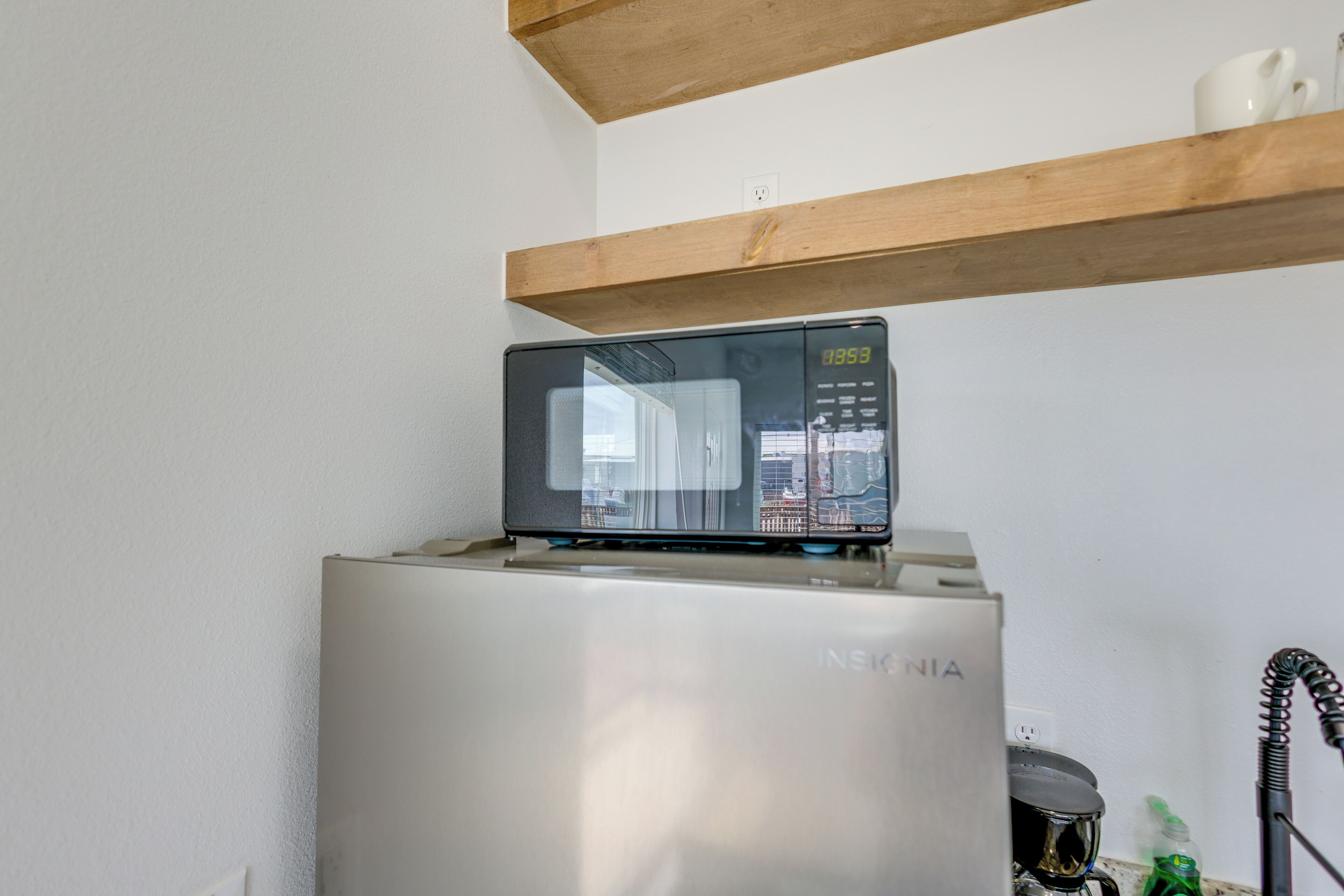 A refrigerator with a digital display and a microwave on top.