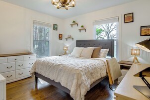 Un dormitorio con cama, mesitas de noche, un escritorio y una silla.