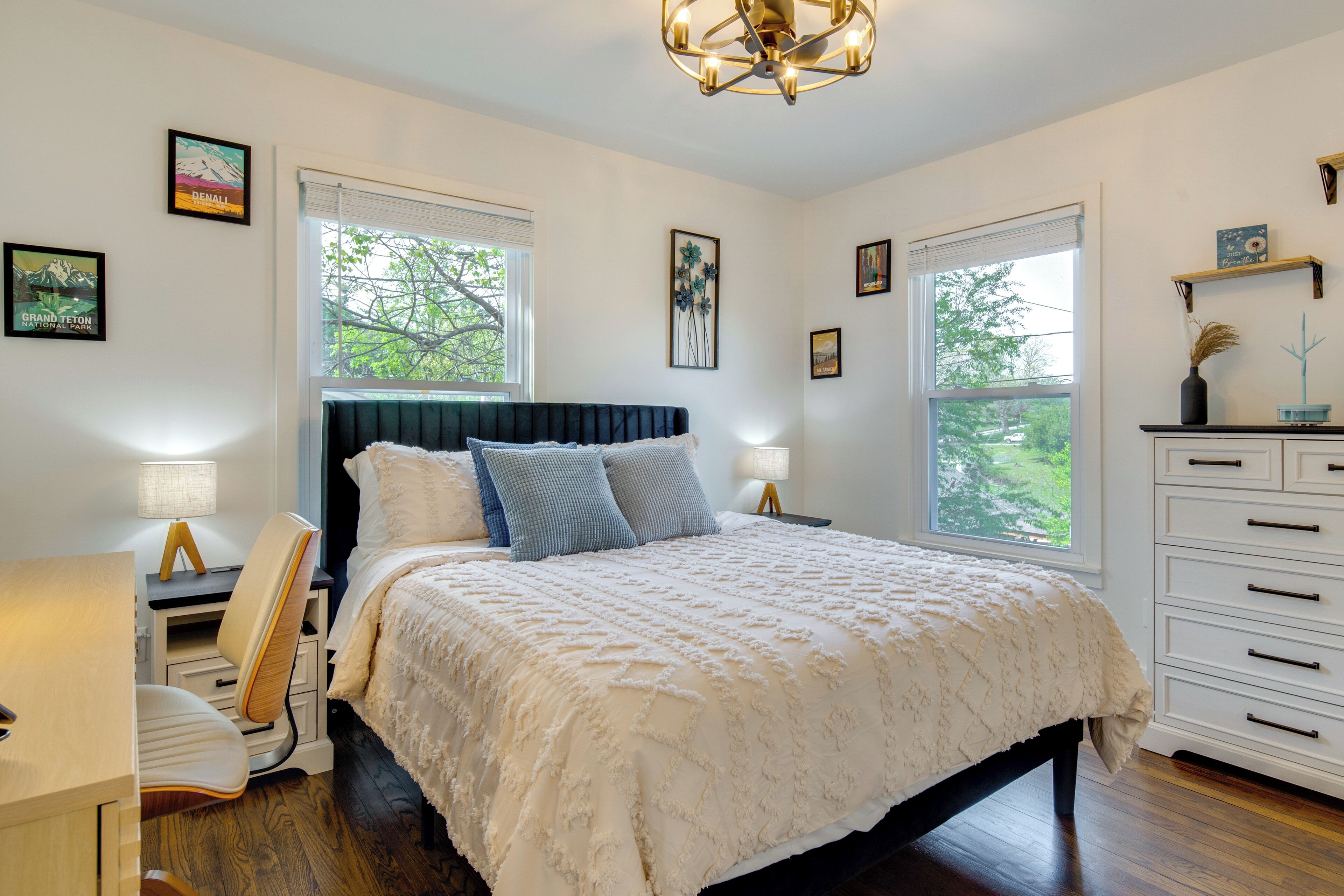 A bedroom with a bed, bedside tables, a desk, and a dresser.