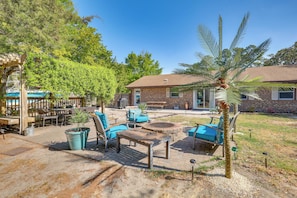 Un patio con mobiliario exterior, una fogata y una palmera.