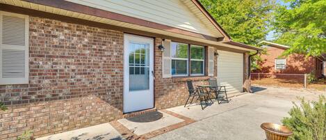 A single-story brick house with a front door, a garage door, and a patio area with a table and chairs.