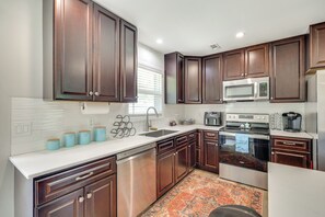 Una cocina moderna con armarios de madera oscura, electrodomésticos de acero inoxidable y encimera blanca.