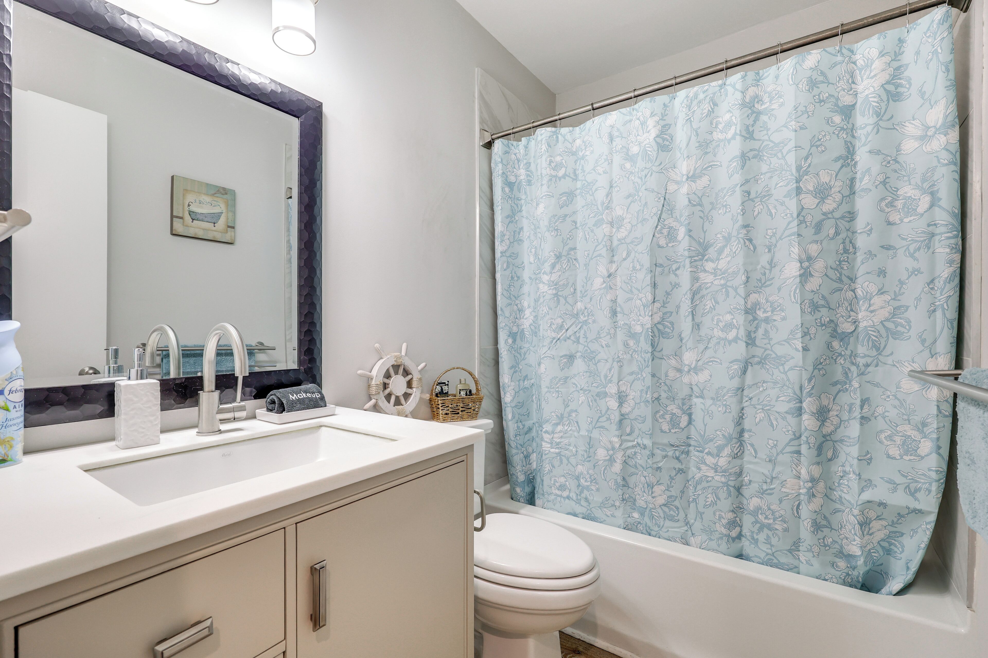 A bathroom with a sink, mirror, toilet, and shower curtain.