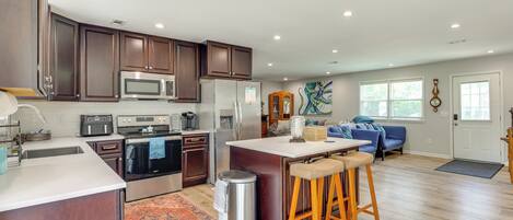 A modern kitchen with stainless steel appliances, wooden cabinets, and a central island with bar stools.