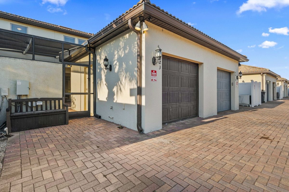 Ein Wohngebäude mit Garage, Bank und befestigter Auffahrt.