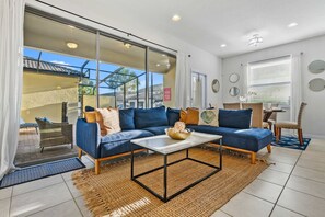 A modern living room with a sectional sofa, a coffee table, and a dining area with chairs. - 5BR Townhome w/ Private Pool·BBQ·Near Disney (Kissimmee)