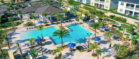 A resort with a central swimming pool, sun loungers, and palm trees.