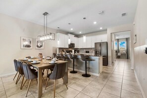 A modern kitchen with white cabinets, a central island, and bar stools. - 3BR Condo·Sleeps 12·Free Waterpark·Near Disney (Davenport)
