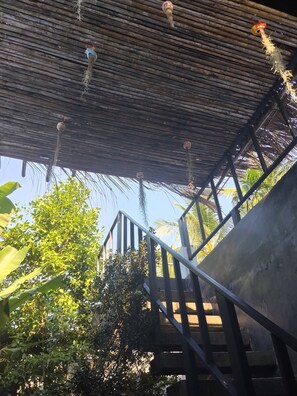 A staircase with a metal railing, a wooden ceiling, and hanging decorations. - Crystal Jungle House - Rooftop Mountain View (Ko Pha-ngan)