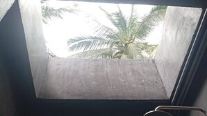 A room with a concrete floor, a window with a view of palm trees, and a metal handle. - Crystal Jungle House - Rooftop Mountain View (Ko Pha-ngan)