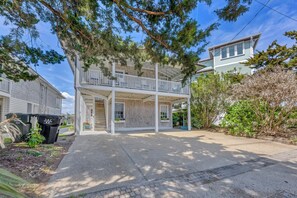 A two-story house with a balcony, a covered porch, and a driveway. - The Dolphin House - 4 bedroom soundfront cottage (Wrightsville Beach)
