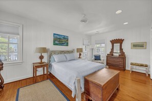 A bedroom with a bed, wooden dresser, bench, and a painting on the wall. - The Dolphin House - 4 bedroom soundfront cottage (Wrightsville Beach)